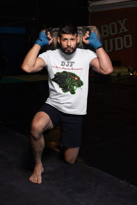 Mann mit DJF by Dean Jayson Freeman T-Shirt und Boxhandschuhen, der eine Fitnessübung in kniender Position ausführt.