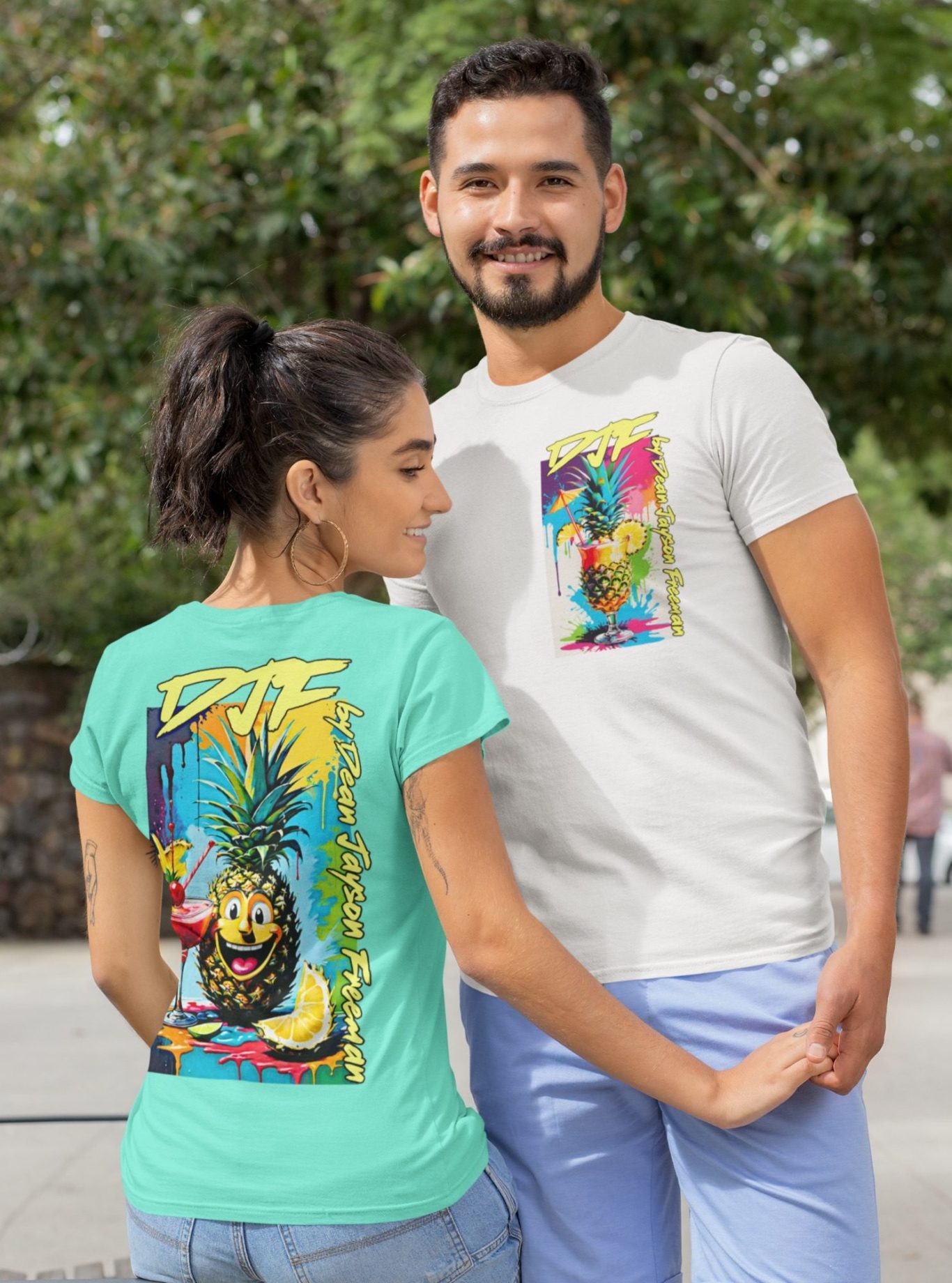 Paar in bedruckten DJF by Dean Jayson Freeman T-Shirts steht im Freien, mit bunten, tropischen Designs auf den Shirts.