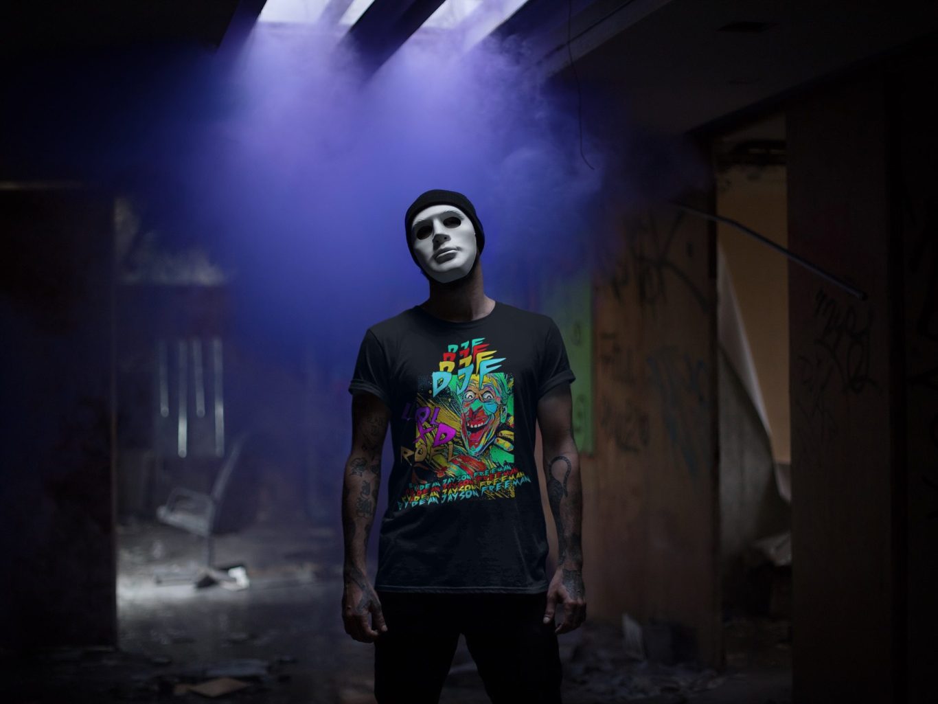 Mann mit Maske und buntem Clown DJF by Dean Jayson Freeman T-Shirt steht in einem rauchigen, verwahrlosten Raum.
